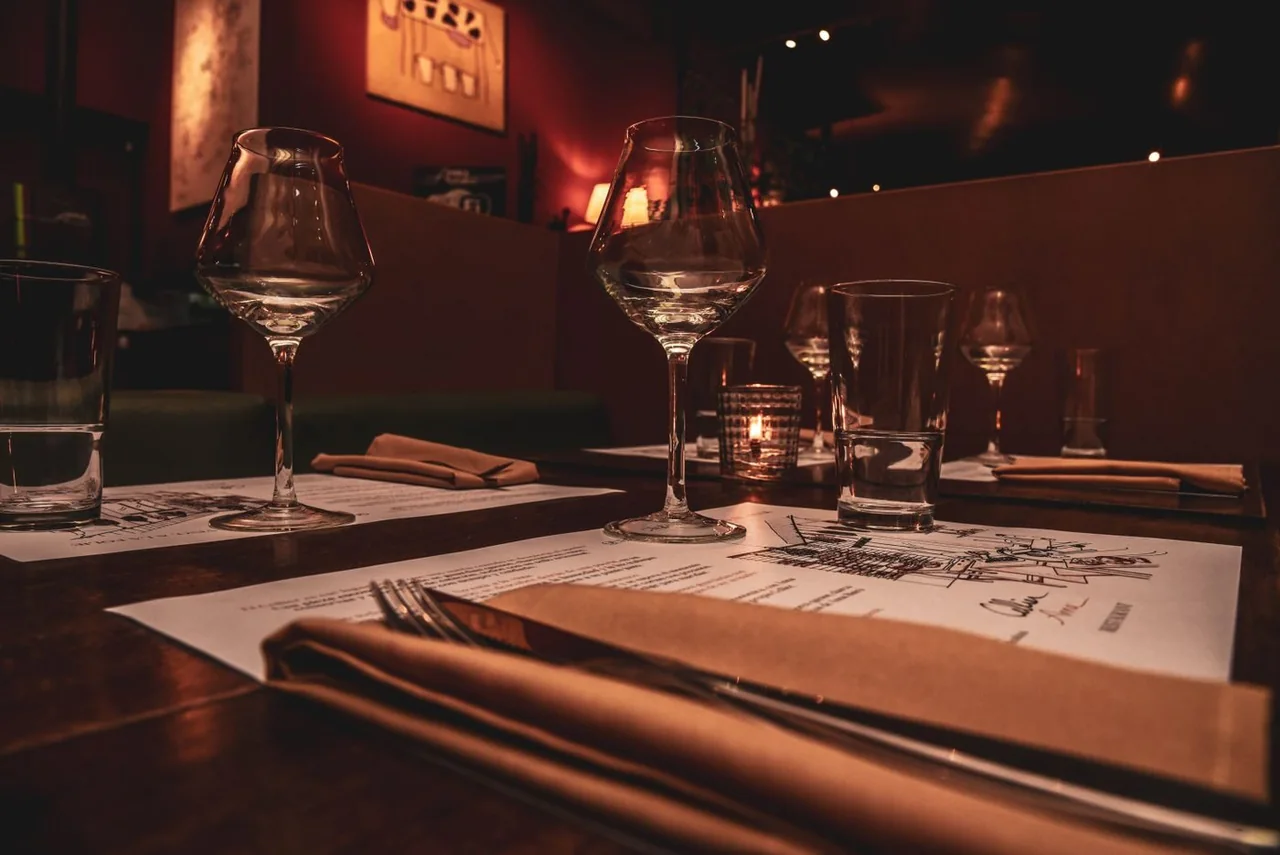 Candlelit restaurant table set with wine glasses, water glasses and folded napkins